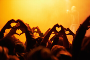 Love and light. Rear view of an audience making heart-shapes with their hands.