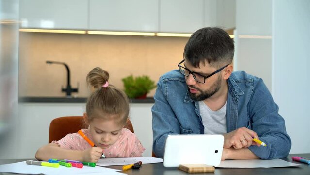 Father and little child learn to draw watching drawing lesson on tablet on internet at home. Online education concept. Video tutorial, drawing training.