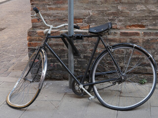 Fototapeta na wymiar Heavily damaged bicycle tied to a pole.