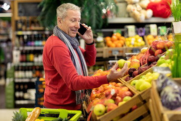 Handsome senior man having phone conversation while shopping