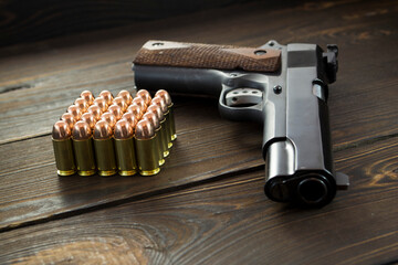 Golden pistol bullets and a gun on a wooden background