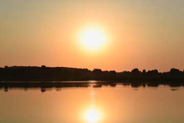 Sunset over the river. Orange evening. Calm lake