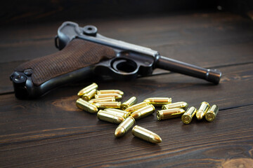Historic Luger P08 Parabellum handgun and shiny 9 mm bullets on wooden vintage background