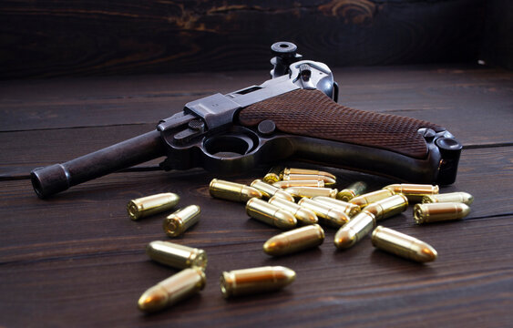Historic Luger P08 Parabellum handgun, old soviet TT handgun and shiny 9 mm bullets on wooden vintage background