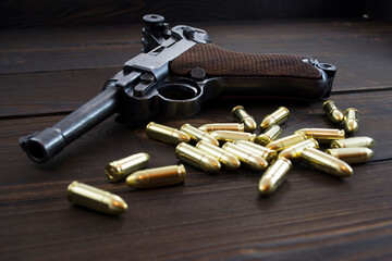 Historic Luger P08 Parabellum handgun, old soviet TT handgun and shiny 9 mm bullets on wooden...