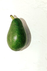 Green ripe avocado on a light background, healthy food concept.