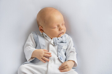 newborn baby boy in a suit sleeping on a  light background. Top view