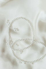 Pearl bijouterie beads on silk texture background.