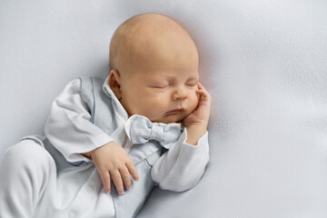 newborn baby boy in a suit sleeping on a  light background