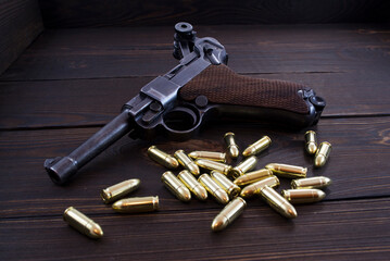Historic Luger P08 Parabellum handgun and shiny 9 mm bullets on wooden vintage background - obrazy, fototapety, plakaty