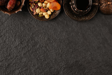 Fasting during Islam Holy Month. Ramadan Kareem. Dates, dried apricots, nut mix and tea in traditional arabian style brass holder at stone surface flat lay with copy space