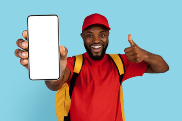 Order Here. Happy Black Delivery Guy With Thermo Backpack Holding Blank Smartphone