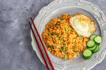 Nasi Goreng Indonesian Chicken Fried Rice with Fried Egg, Chili Sauce and Cucumber Top Down Photo

