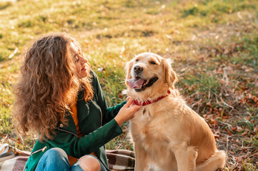 Golden retriever dog with a curly woman walking outdoors on sunny day. Training the dog in the...
