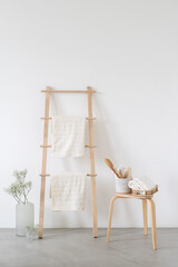 Massage brush, sponge, toiletries near wooden ladder with towels