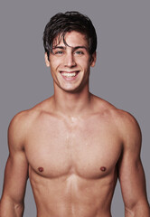 Fototapeta premium Hes got the perfect body and smile. Portrait of a handsome young shirtless man posing in the studio.