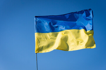 Ukrainian flag on a flagpole. blue sky background