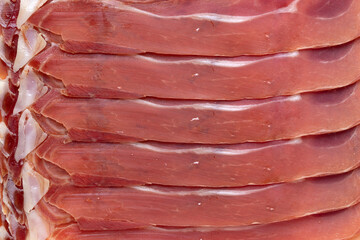 Sliced Spanish raw ham, serrano ham, close up full frame as background