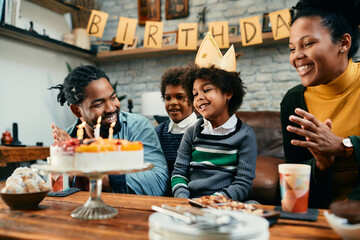 Happy African American family have fun while celebrating little girl's Birthday at home.