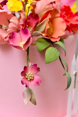 closeup of pink flowers on a branch on the surface of the cake
