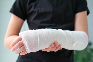Close-up of a broken arm of a child in a cast. The girl holds her hand bent on the background of a...