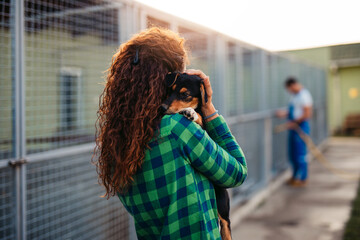 Young adult woman holding adorable dog in animal shelter.