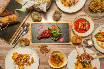 Set of Indian food dishes with basmati and kashmir rice, red curry, onion bhaji, chicken tikka masala, vegetable samosa, aromatic spices, korma, tomato and lettuce