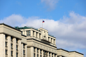 Russian flag on the parliament building in Moscow on background of blue sky and white clouds....