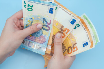 Woman's hands counting stack of euro banknotes on blue background. Money. Business. Finance - obrazy, fototapety, plakaty