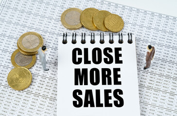 On financial reports there are figurines of people, coins and a notepad with the inscription - Close More Sales