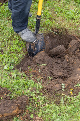 Digging the earth with a spade at countryside. Male foot wearing a rubber boot digging the earth with a spade. iron shovel stuck in the ground.preparing for garden work. photo in natural light