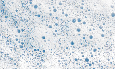 White soap foam surface or shower gel shampoo with bubbles. Abstract cosmetic blue background texture. Selective focus.