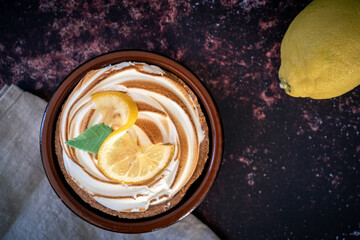 Traditional french lemon tart on a dark rusty table. lemon and napkin as decoration. View from above