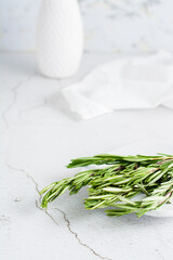 Sprigs of fresh rosemary on a plate on the table. Organic aromatic herb for cooking and health. Vertical view. Copy space