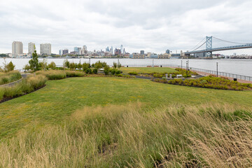 Fototapeta na wymiar Looking out over the grassy field and landscape architecture at RCA Pier Park, an urban revitalization project on the Delaware River waterfront in Camden, New Jersey, USA
