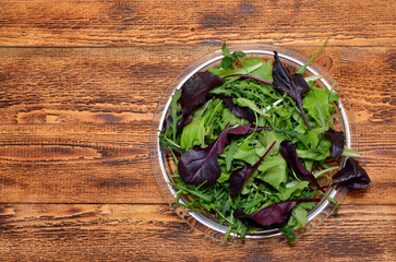plate with fresh lettuce leaves on wooden background, flat lay, copy space