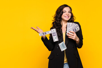 Rich carefree woman squanders money. Girl with stack of cash one hundred dollar bills in black...