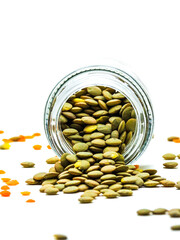 Red lentils in glass bottle, overturned glass jar, scattered lentils. Selective foc us on little.