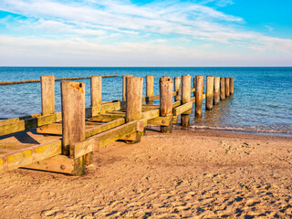 Sonniger Wintertag an der Ostsee, alter Steg am Strand im warmen Morgenlicht	