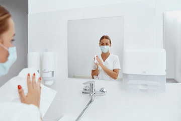 Hygiene, health care. Woman doctor or nurse drying hands with paper tissue at hospital after...
