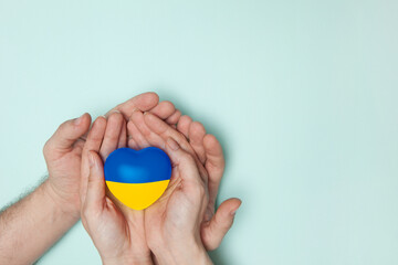 Heart with print the national flag of ukraine in female and male hands. Flat lay.