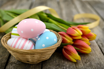 Obraz na płótnie Canvas Colorful Easter eggs and tulips on wooden background