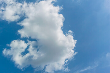 A large white cloud with jagged edges against a deep blue sky