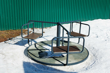black merry-go-roung isolated in winter.
Child playground with carousel with three seats