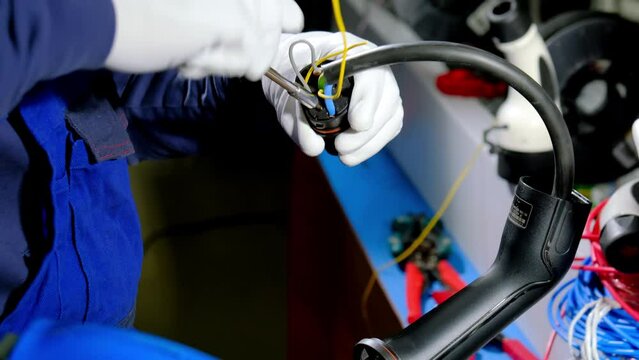 Electrician twists wires with screwdriver creating pump plug to charge e car. Professional worker deals with cable at portable charging station close view
