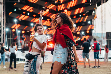 Obraz premium Two beautiful friends drinking beer and having fun on a music festival
