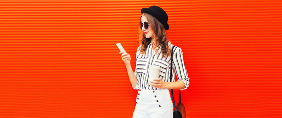 Stylish young woman model with smartphone wearing black round hat and striped white shirt on red...