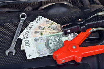 Polish money currency and ring spanner and electricity jumper cables to charging car battery
