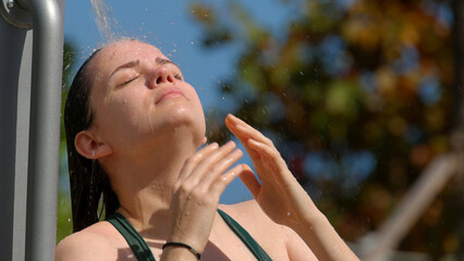Naklejka premium Young woman taking a shower after sun bathing at the beach - close up shot
