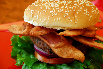 Beef burger with fried sausage on a wooden table, close up view
